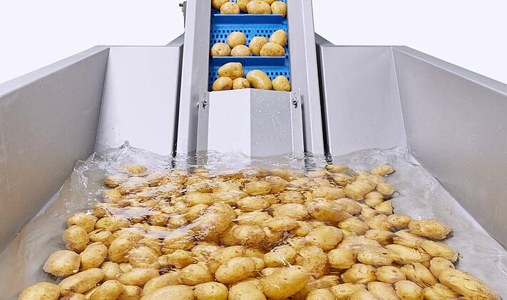 Le convoyeur à trémie d'eau de KRONEN permet, grâce à un trempage court, le pré-nettoyage des pommes de terre - la terre qui colle et les petits cailloux sont éliminés.