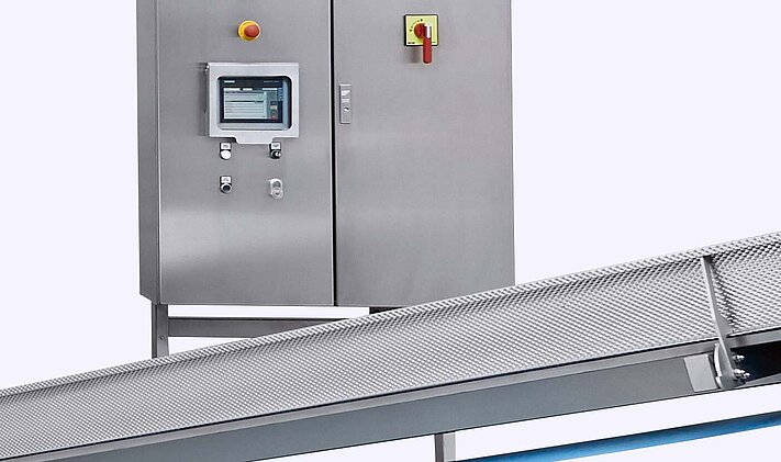 Alongside the large centrifuge, the K650 drying system from KRONEN includes a freestanding control cabinet and an infeed and discharge belt