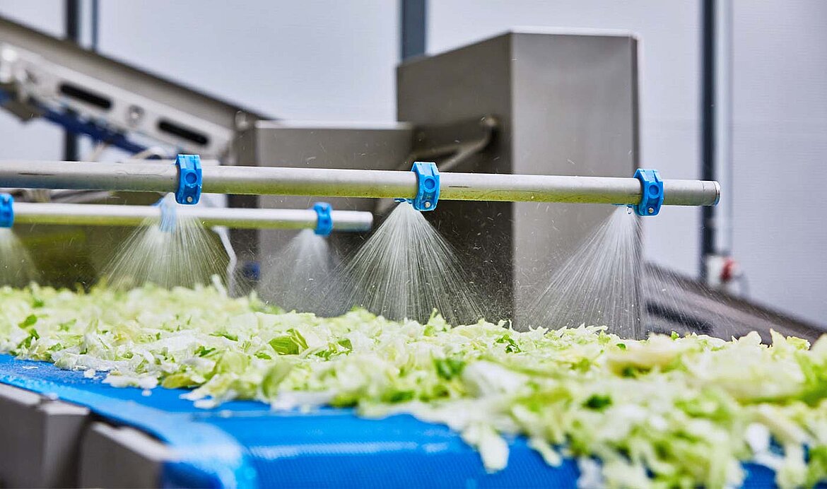 Fresh water spray of the GEWA washing machines from KRONEN rinses and cleans the product during discharge out of the machine